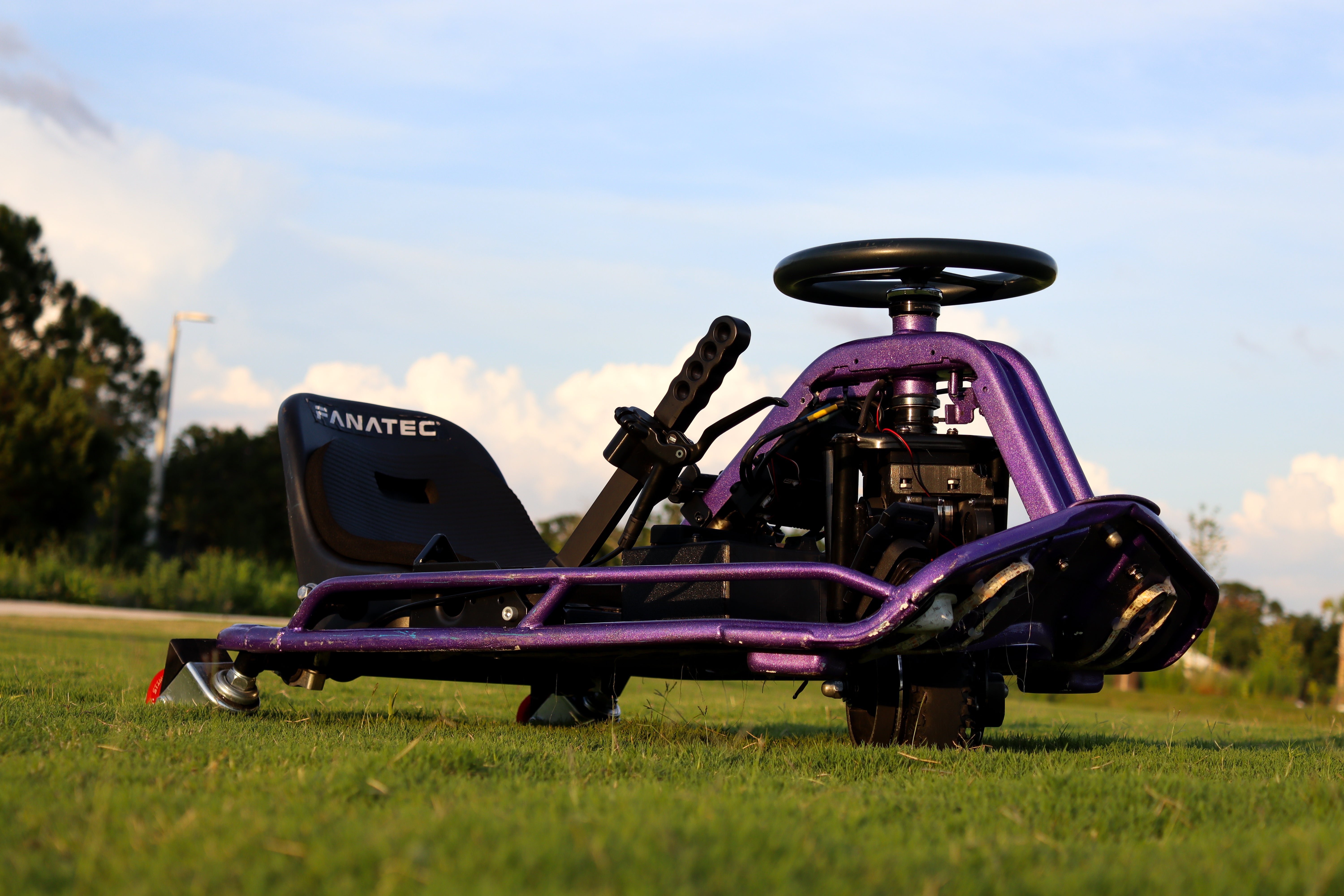 Purple go-kart on grass with a clear sky